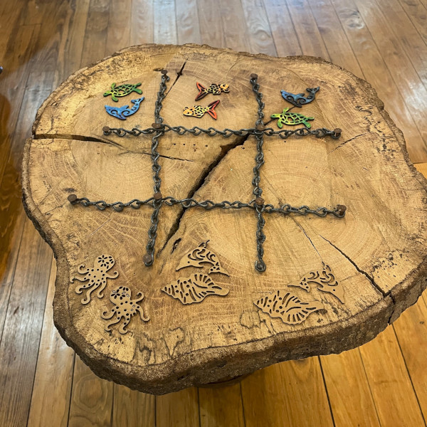 A tic tac toe board made from the crossection of a log and chains to make the lines